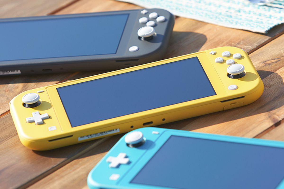 Three Nintendo Switch Lites laying on a table. One is yellow, one is grey, and the other is turquoise.