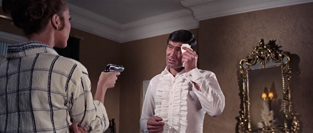 Diana Rigg as Tracy points a gun at George Lazenby as Bond in On Her Majesty’s Secret Service