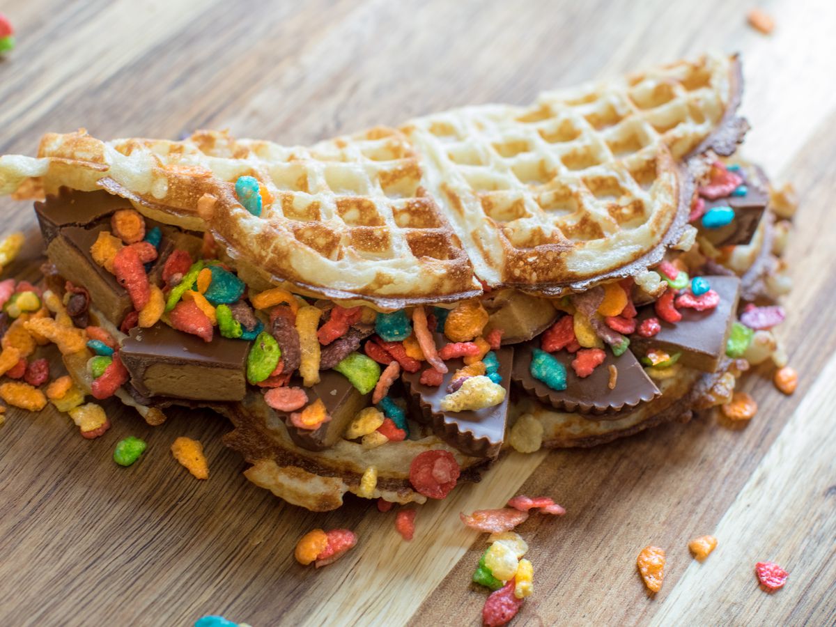 A folded over waffle is stuffed with peanut butter cups and fruity pebble cereal