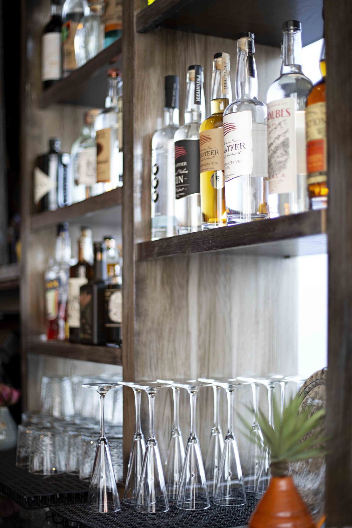 Close-up of a restaurant bar with bottles of liquor on a wooden shelf above overturned clean flute glasses