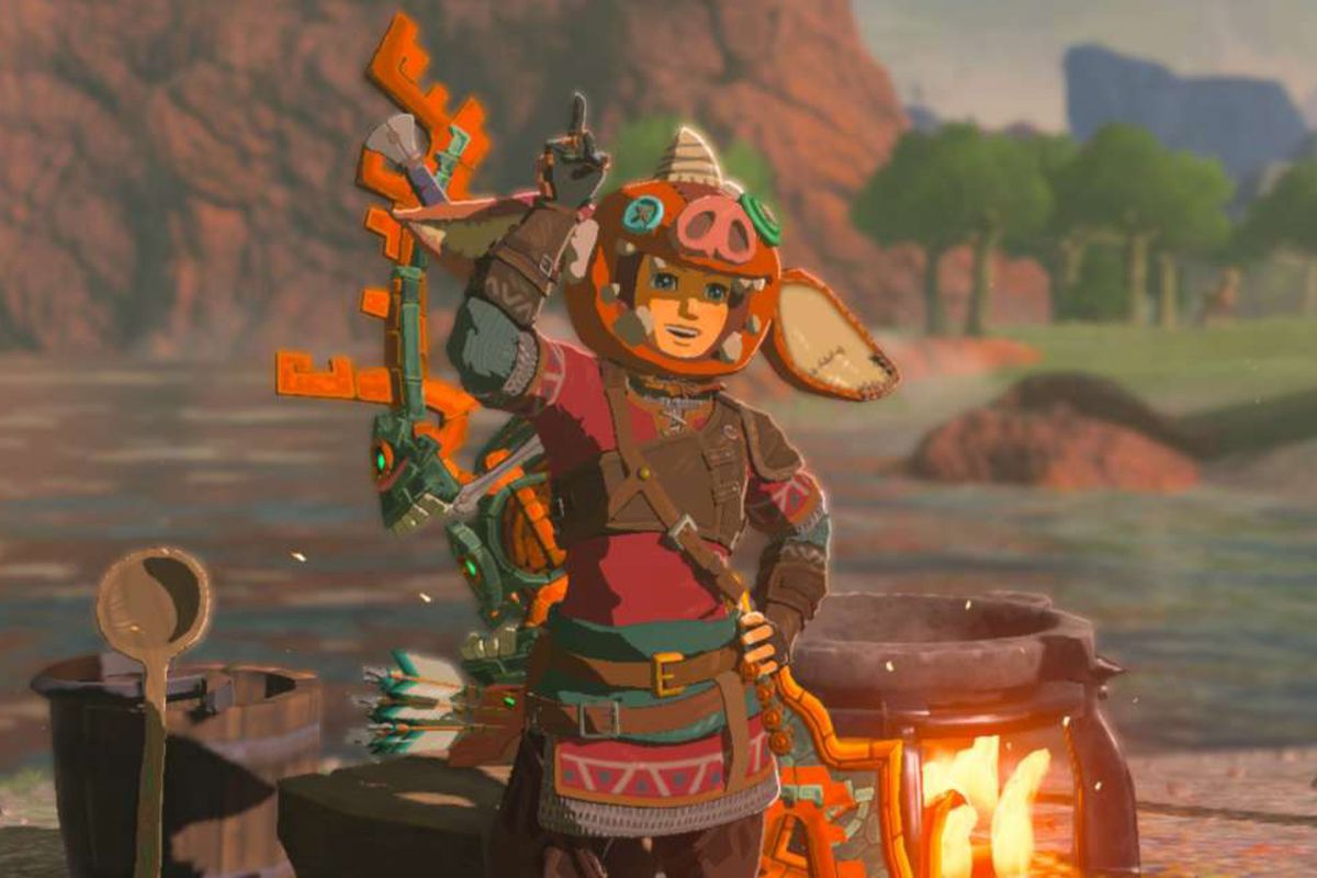 Link, wearing a Bokoblin hat, standing in front of a cooking pot and soup ladle. He’s posing in a cute way.