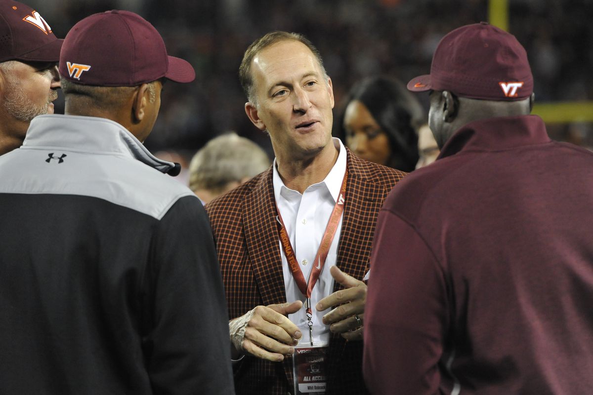 Athletic Director Whit Babcock of the Virginia Tech Hokies (center) speaks to Virginia Tech hall of famers Dell Curry and Bruce Smith prior to the game against the Clemson Tigers at Lane Stadium on September 30, 2017 in Blacksburg, Virginia.