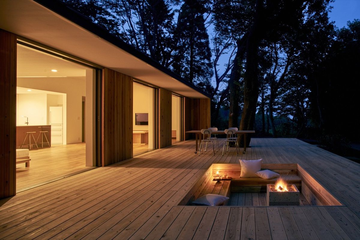 A single-story house has three openings to a deck with recessed seating area.