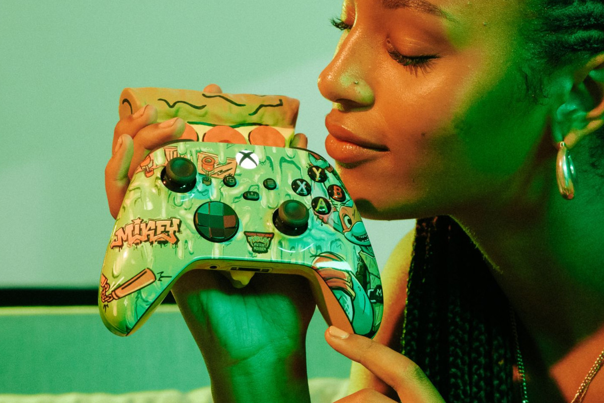 A promotional shot of a new Xbox Controller, along with a pizza scent diffuser attached to the back. A young woman is holding the controller and enjoying the pizza scent.