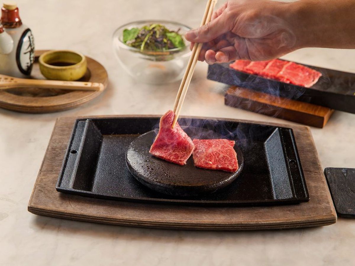 Austere pieces of Kobe beef cooking on a hot plate, tableside.  