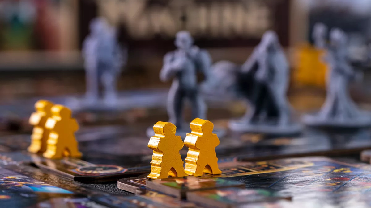 Two yellow pawns in the foreground, with gray, delicately sculpted plastic miniatures in the background. From City of the Great Machine.