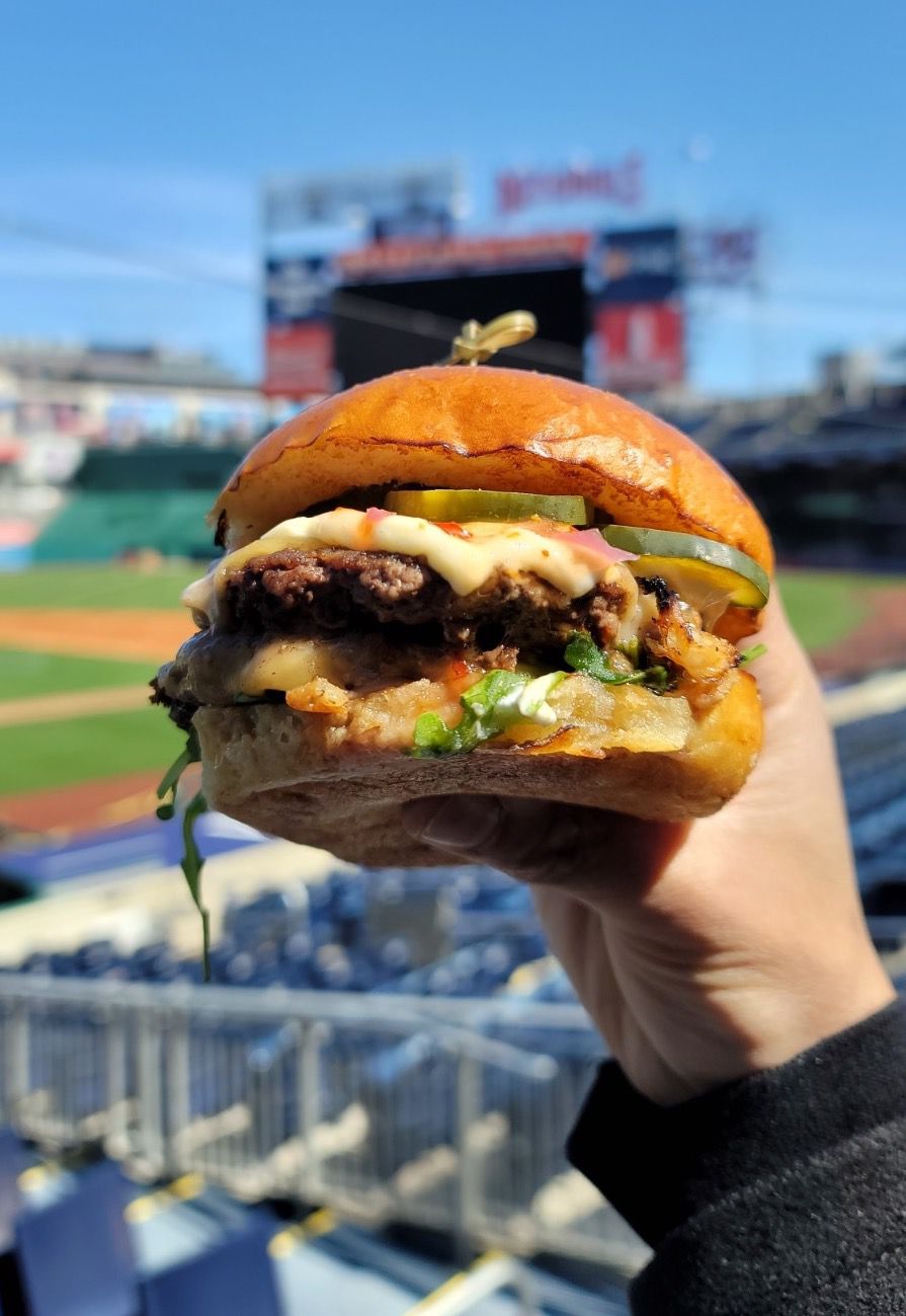 A burger held up in front of a stadium