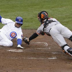 Chicago Cubs' Welington Castillo, left, scores on a single hit by Brent Lillibridge as San Francisco Giants catcher Buster Posey, right, dives in with the late tag during the third inning of a baseball game in Chicago, Thursday, April  11, 2013. 
