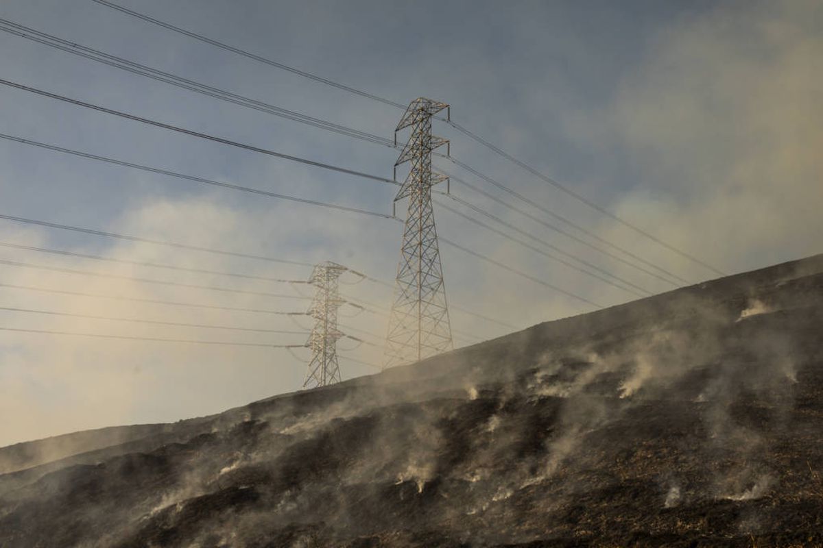 Smoke rises from a hillside beneath PG&amp;E transmission lines