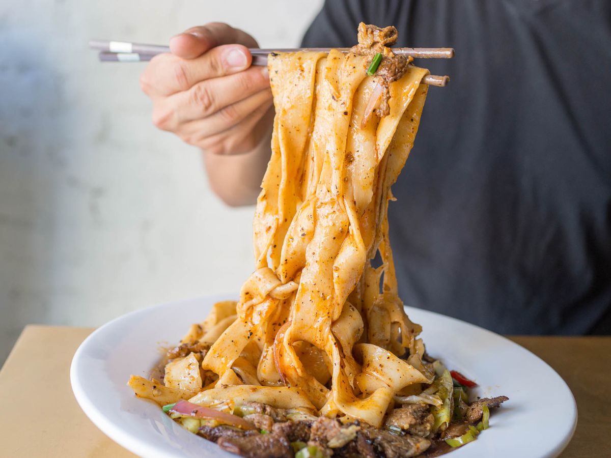 Hand-pulled spicy cumin lamb noodles being lifted with chopsticks