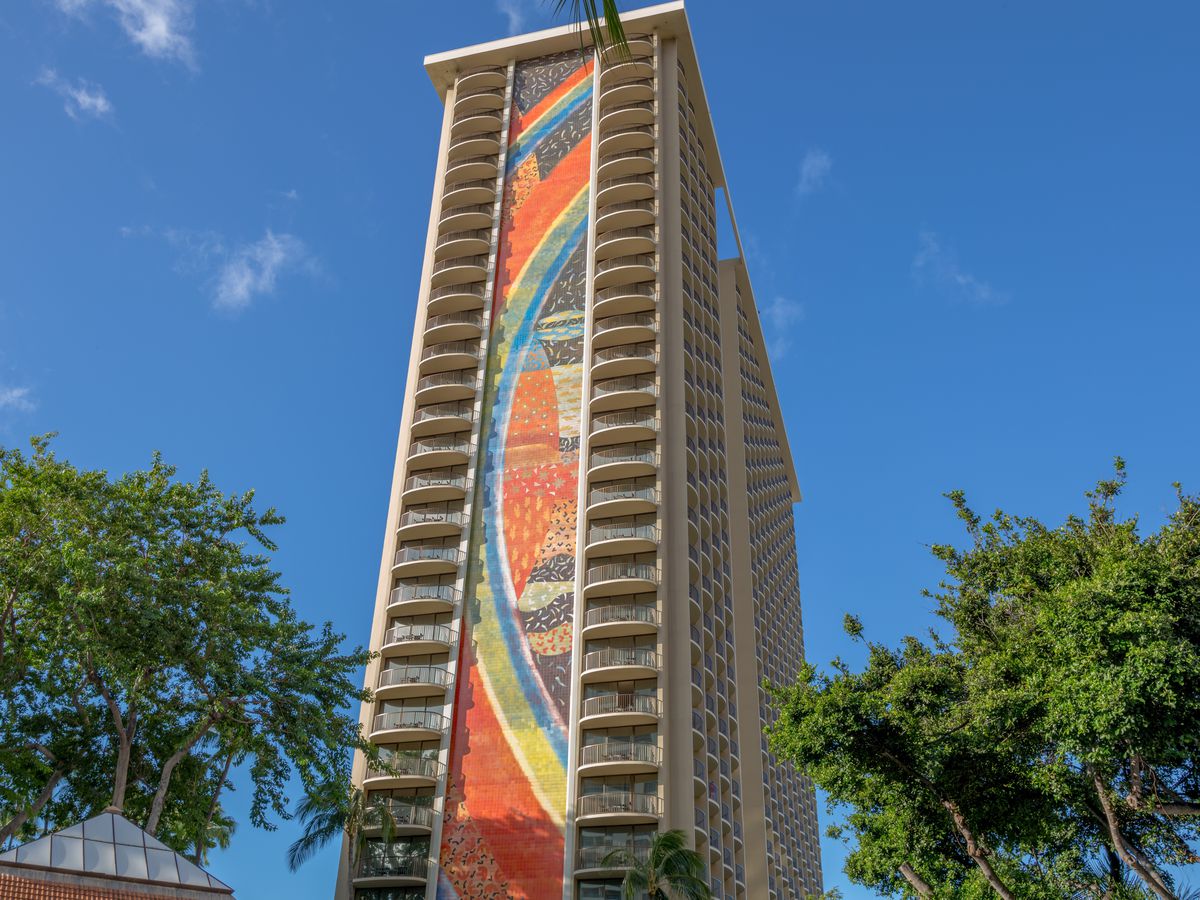 A view of the side of a hotel entirely covered by a rainbow mosaic mural.