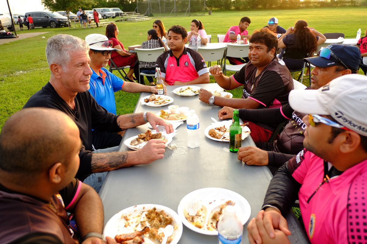 bourdain eating at a table with cricket players in houston