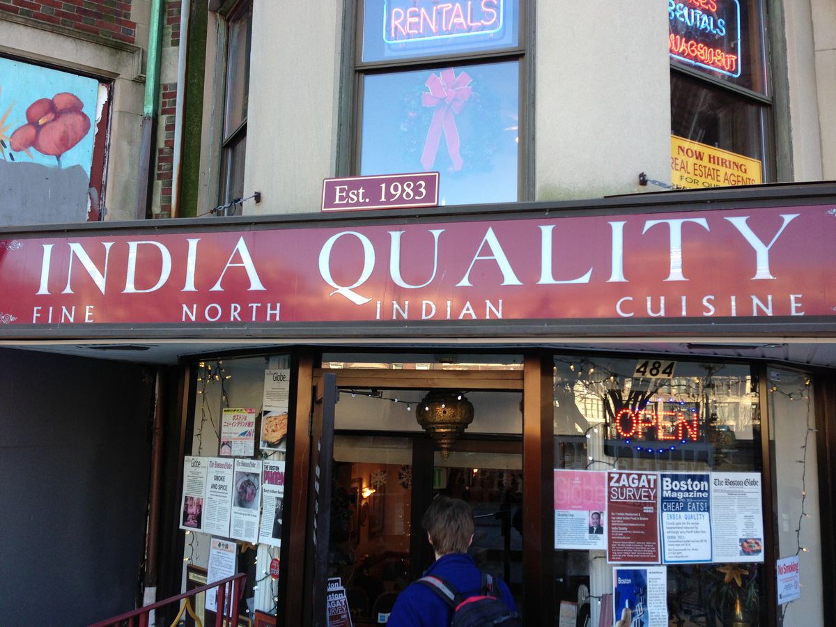 The exterior of a restaurant. A large read sign says “India Quality, Fine North Indian Cuisine, Est. 1983”