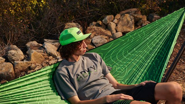 a photo of a young person sitting on a bright green xbox-themed hammock 