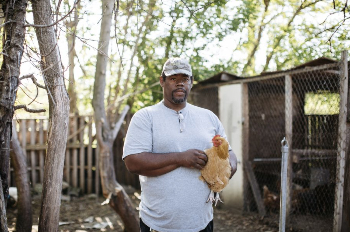 A man holds a live chicken