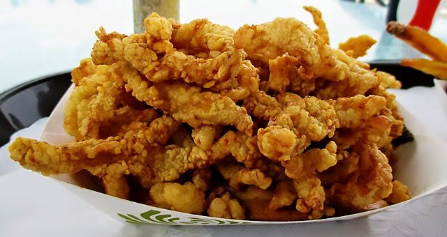 White paper container full of fried clams, stacked high