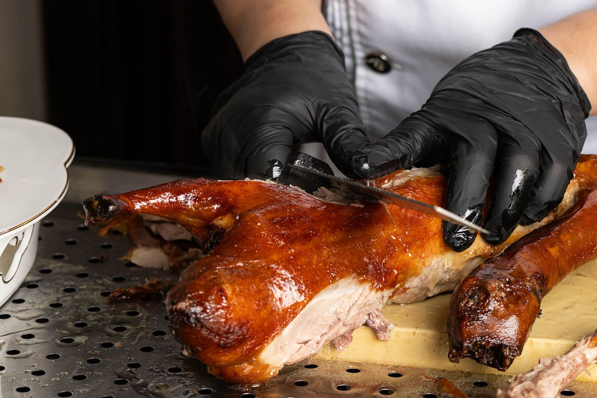 A chef slices a roast Chinese duck tableside.