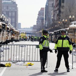 Boston police officers stand on Boylston Street near empty buses meant to transport runners who were instead diverted from the course following an explosion at the finish line, Monday, April 15, 2013, in Boston. 