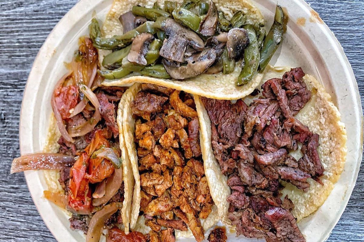 An overhead shot of four tacos with lots of meat on a plate.