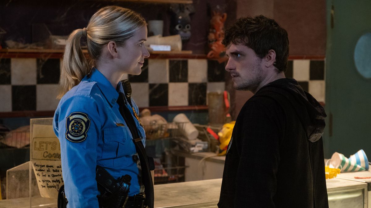 Bruised and wild-eyed, night security guard Mike (Josh Hutcherson) faces off against perky-looking cop Vanessa (Elizabeth Lali) in the Five Nights at Freddy’s movie