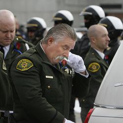 Pallbearer and Utah County Sheriff's officer Lance McDaniel wipes his eyes after escorting the casket carrying Utah County Sheriff's Sgt. Cory Wride into the funeral coach at the UCCU Event Center at Utah Valley University in Orem on Wednesday, Feb. 5, 2014.  Wride was killed in the line of duty on Thursday while conducting what initially appeared to be a routine traffic stop.  Wride was a deputy with the sheriff's office for 19 years and leaves behind a wife, five children and eight grandchildren. 