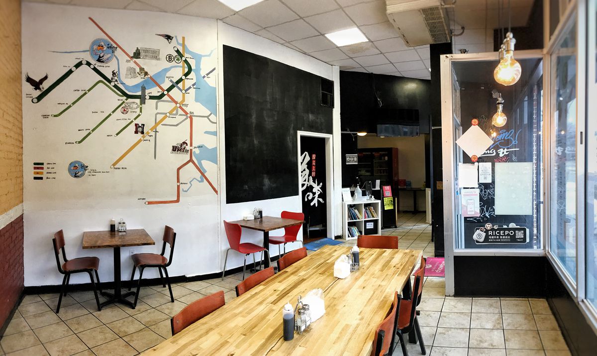 Interior photo of a small, very casual restaurant. One wall features a large mural of Boston’s subway system map.