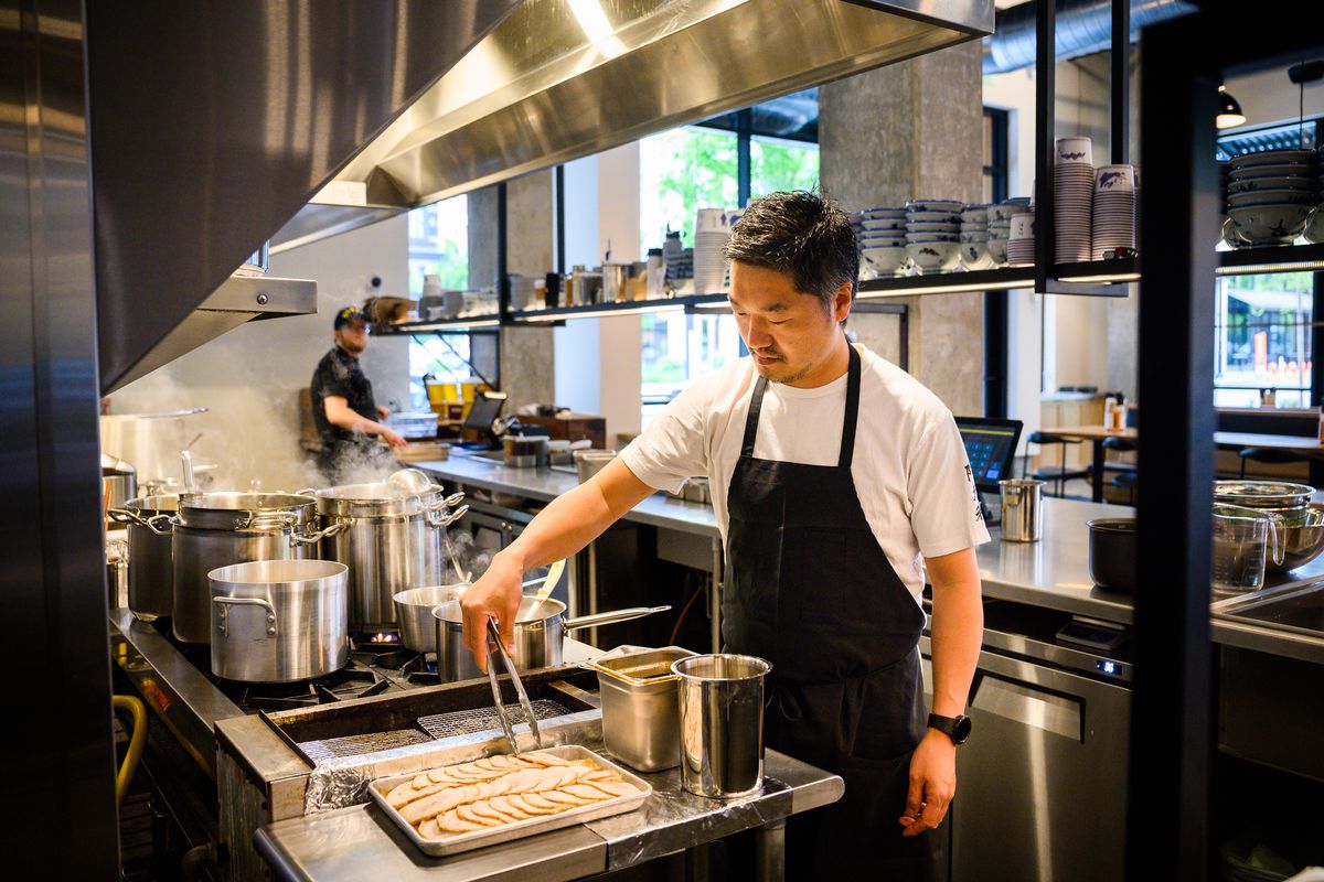 A man in a black apron grabs pieces of thinly sliced pork at Afuri in Portland, Oregon.