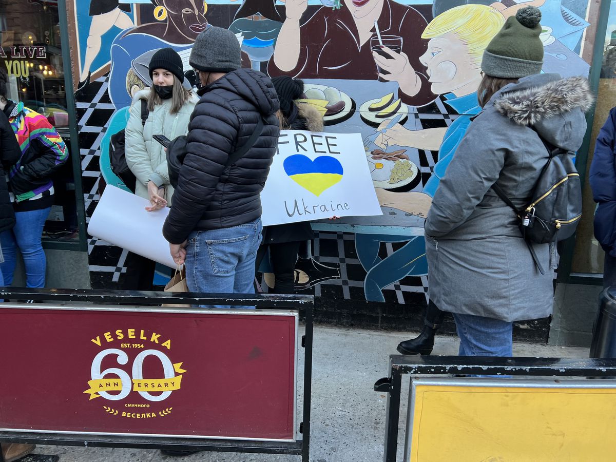 People, some carrying signs supporting Ukraine, waiting in line outside of Ukrainian restaurant Veselka in the East Village.