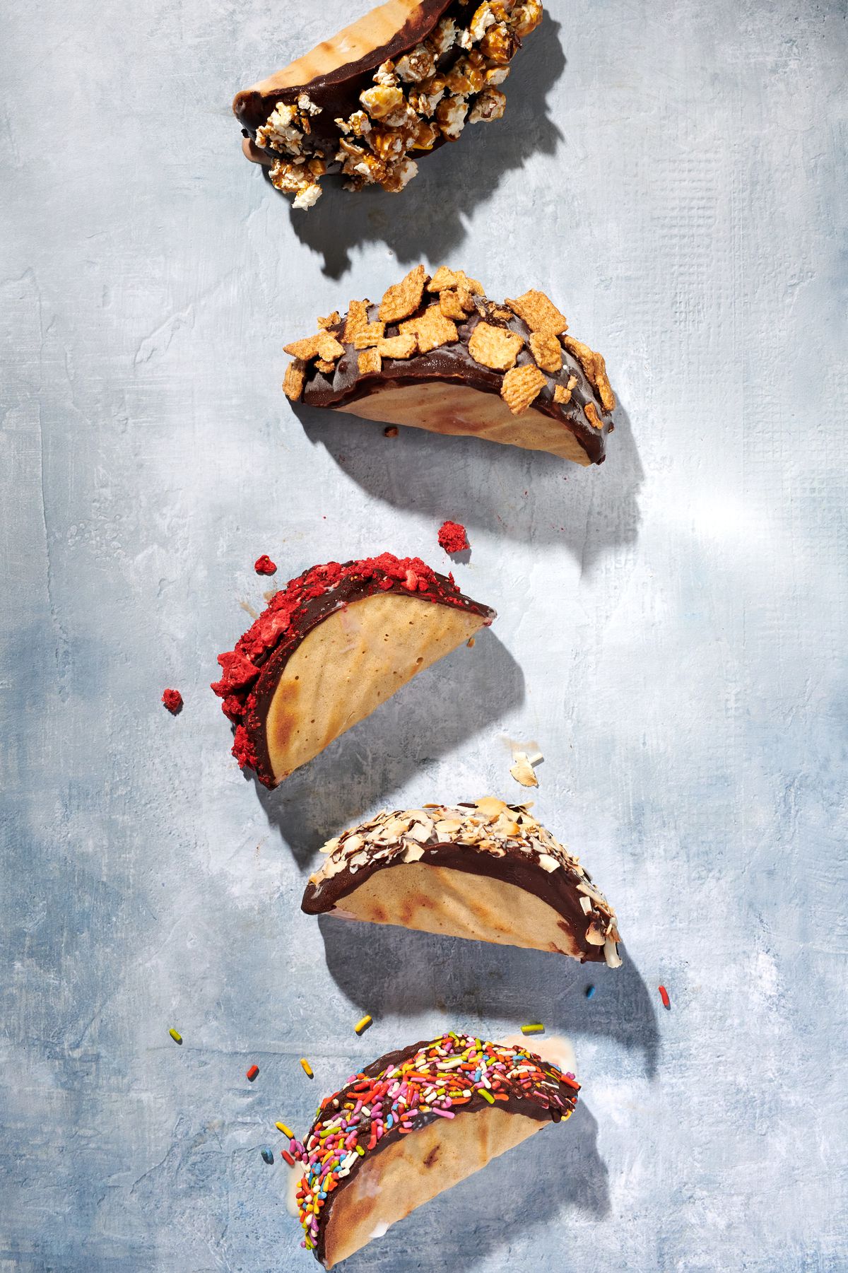 A row of ice cream tacos, topped with colorful toppings.