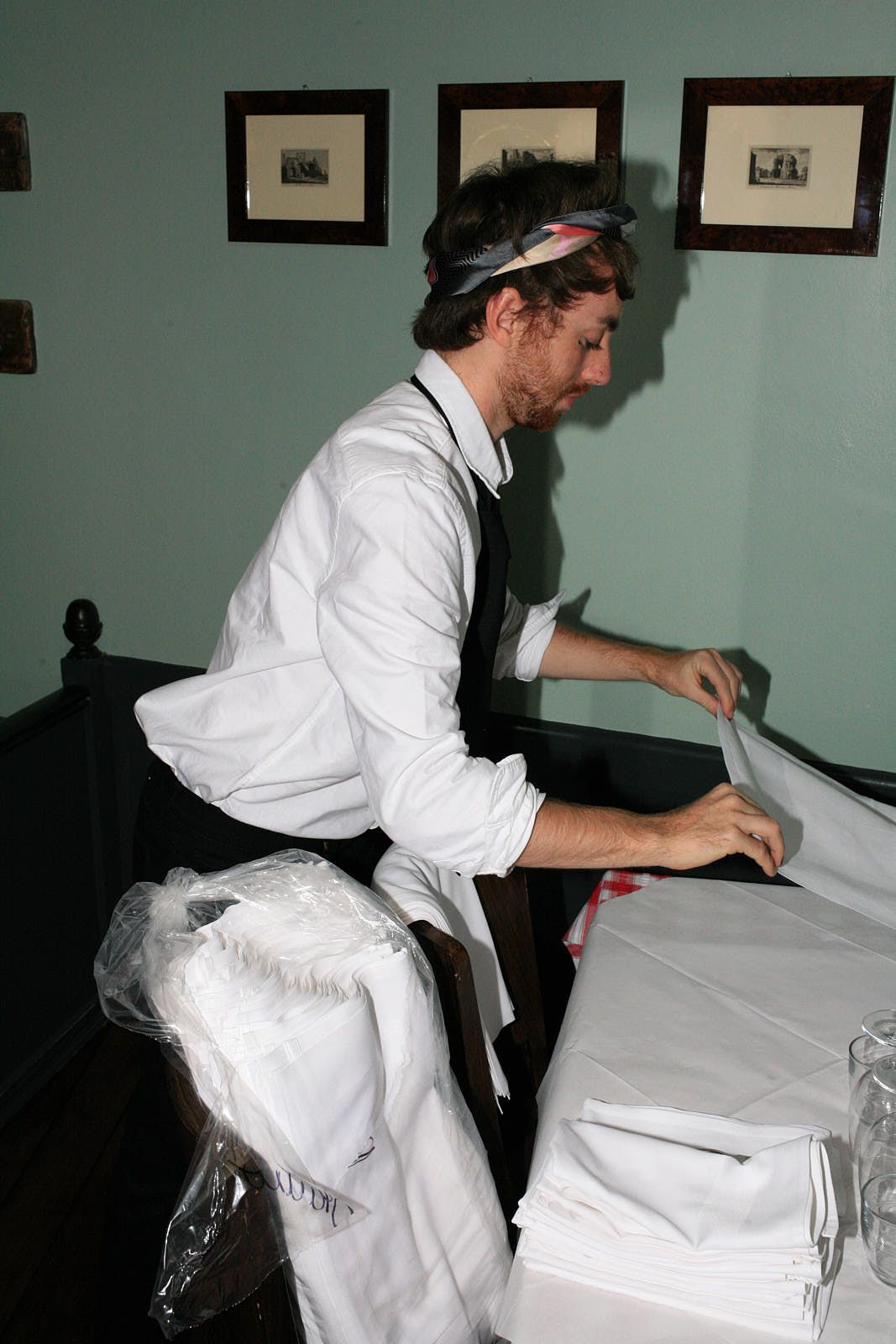A waiter prepares napkins for service at Brutto, unfurling them before folding.