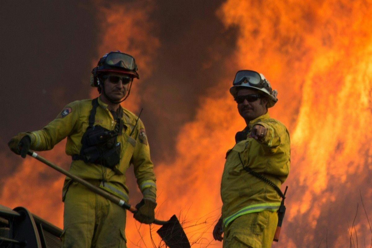 Two firefighters monitor the Blue Cut Fire as flames scorch a hillside near Wrightwood, California.