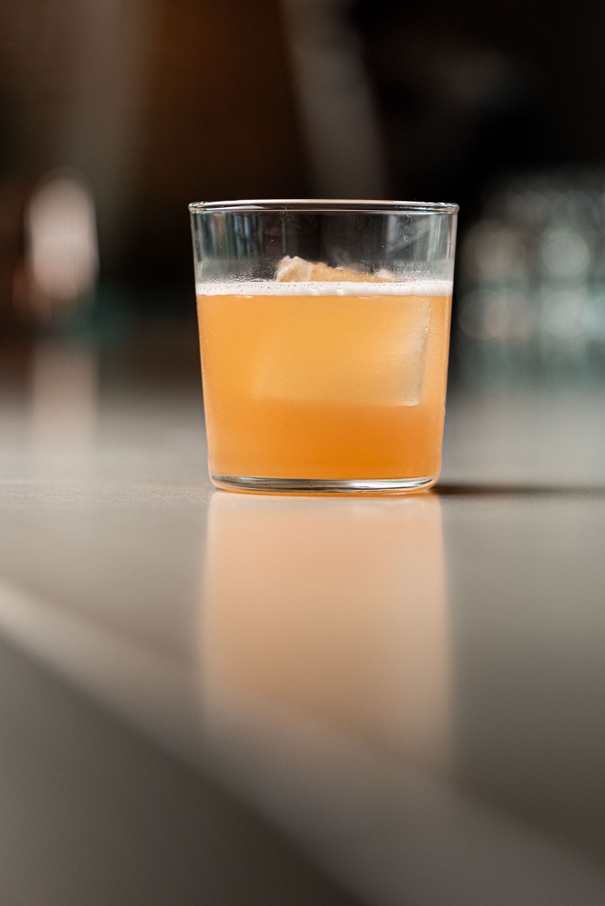 A light orange cocktail in a tall glass shown from the side.