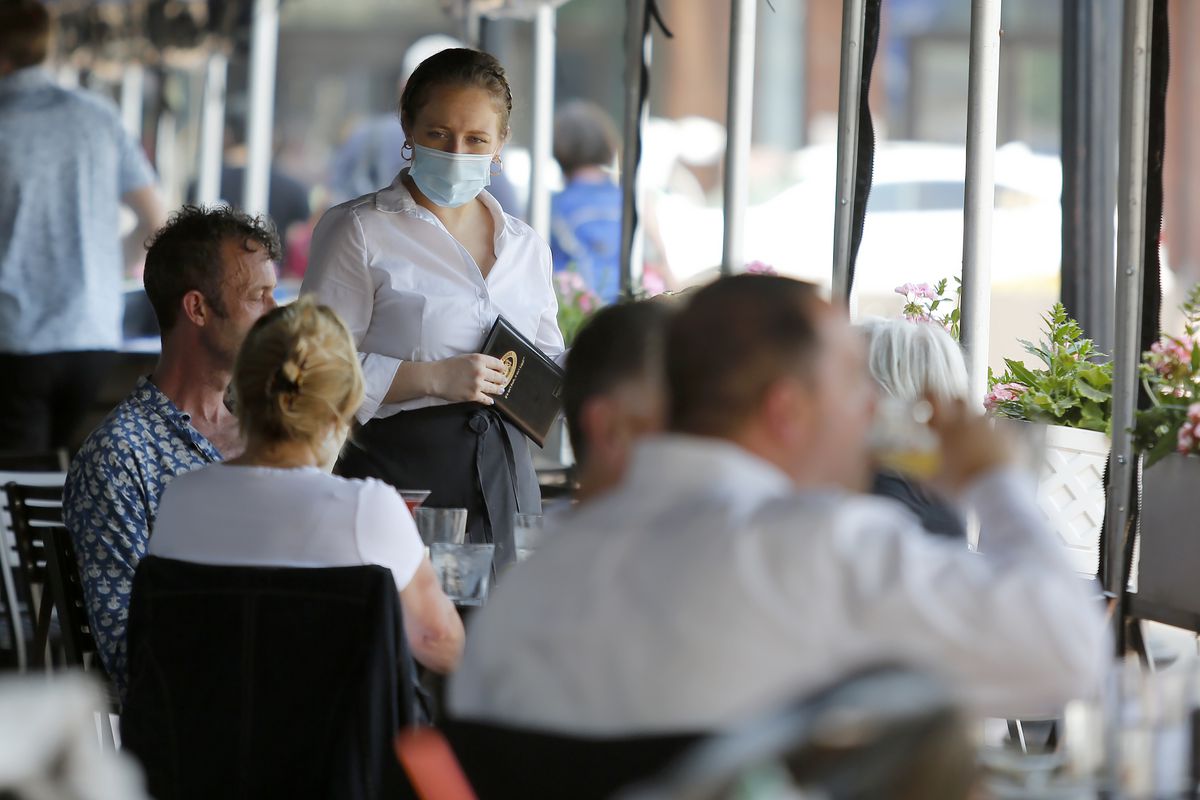 A server prepares to take an order from customers seated outside at Legal Sea Foods, Wednesday, May 26, 2021, in Boston.