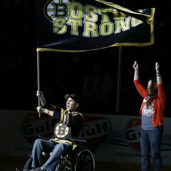 Richard Donohue, the Massachusetts Bay Transportation Authority officer wounded during the shootout with the Boston Marathon bombing suspects, waves a "Boston Strong" banner as his wife, Kimberly, raises her arms during ceremonies prior to Game 3 of the Eastern Conference finals in the NHL hockey Stanley Cup playoffs between the Boston Bruins and the Pittsburgh Penguins, in Boston on Wednesday, June 5, 2013.