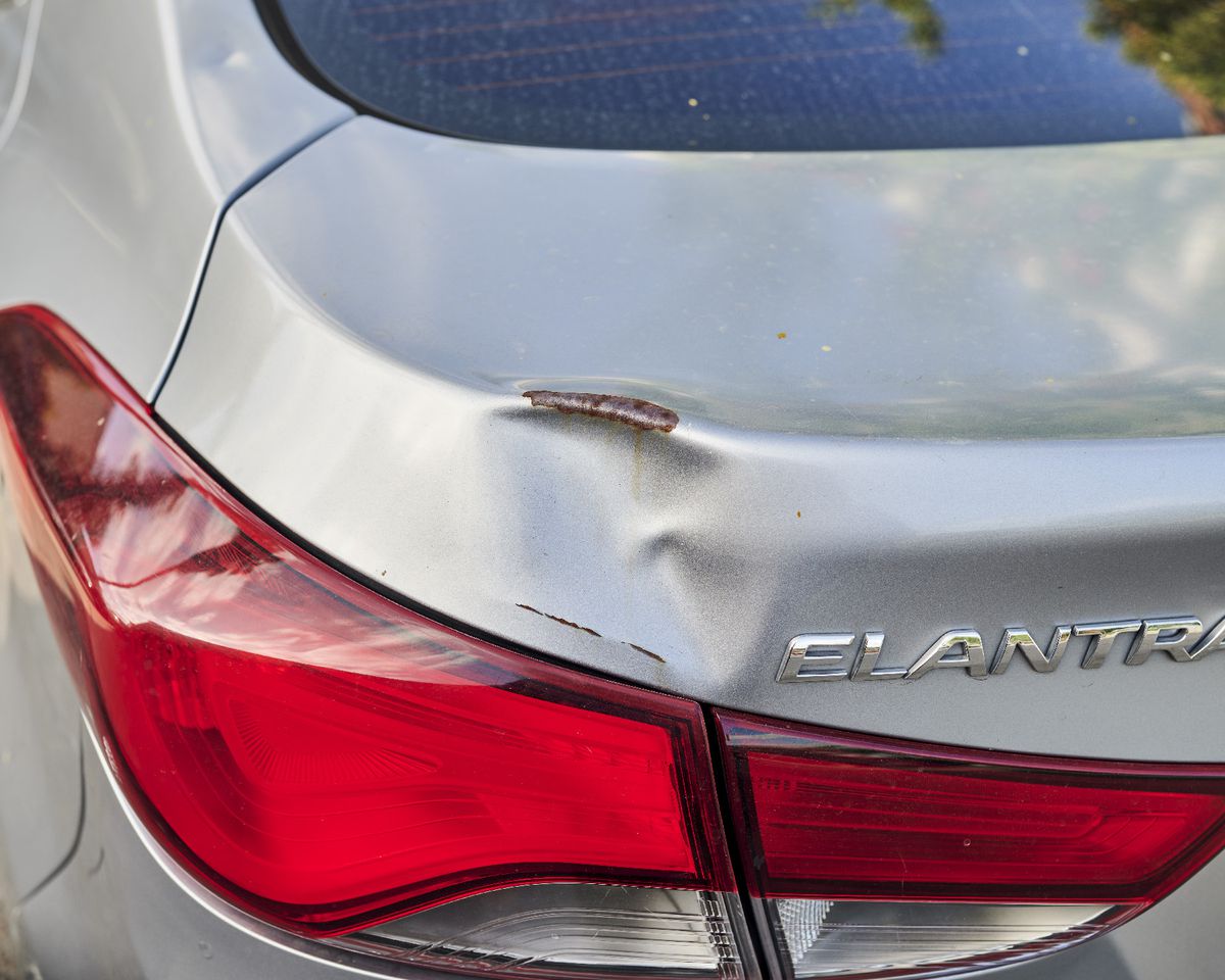 A photo showing a dent on the rear quarter panel of a silver Hyundai Elantra.