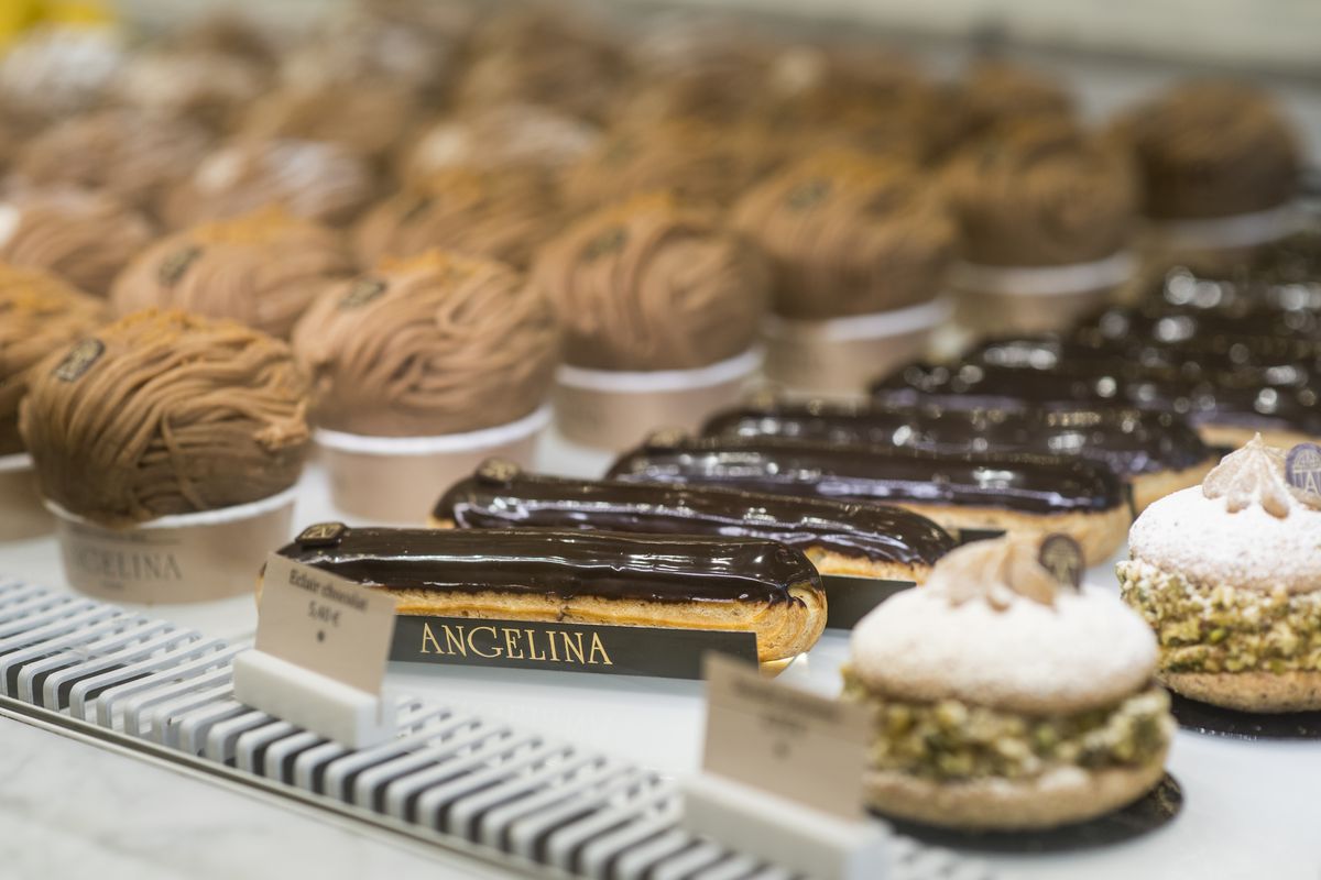 A row of pastries can be seen sitting on a shelf behind a glass wall