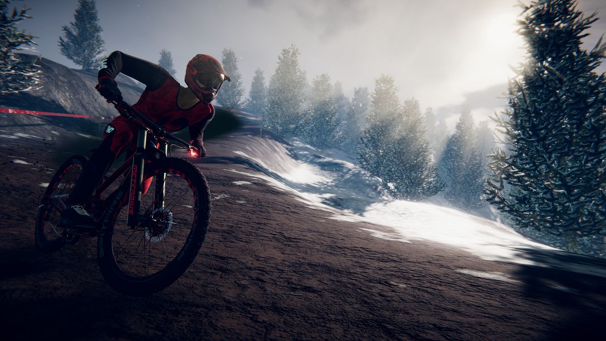 descenders man biking down hill with sunlight trees behind him