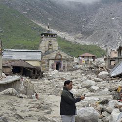 In this Thursday June 20, 2013, photo, a  pilgrim takes pictures of an area devastated following heavy monsoon rains at Kedarnath, in the northern Indian state of Uttrakhand. A joint army and air force operation are trying to evacuate thousands of people stranded in the upper reaches of the state of Uttrakhand where days of rain had earlier washed out houses, temples, hotels and vehicles leading to deaths of over a hundred people amid fears that the death toll may rise much higher. (AP Photo)