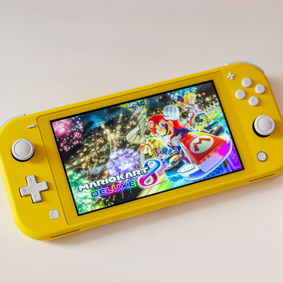 a yellow Nintendo Switch Lite with the Mario Kart 8 Deluxe homescreen on it