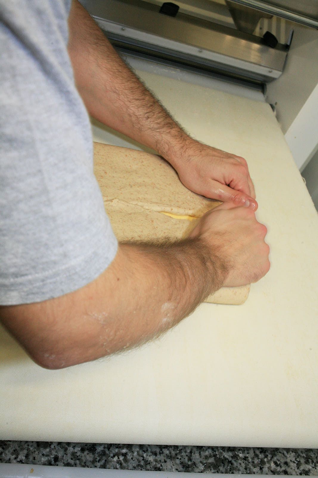 A baker folds dough over a block of butter, preparing it for lamination
