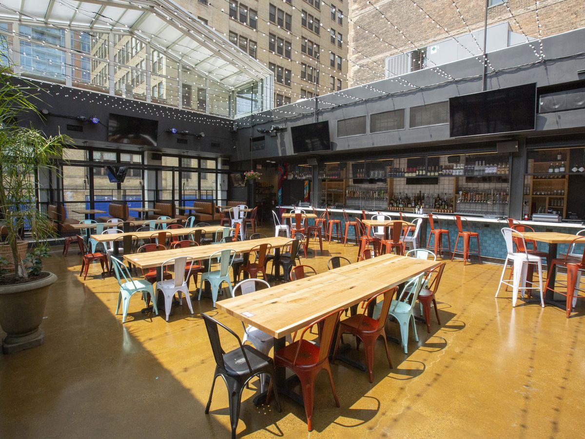 A large dining room filled with long tables under a retractable roof. 