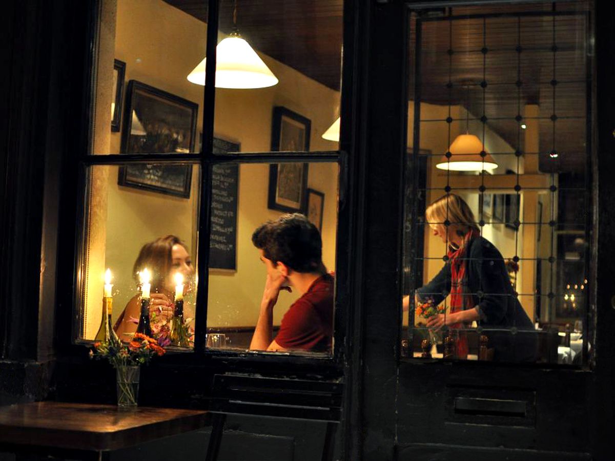Candlelit dinner at Andrew Edmunds, in Soho, seen through the restaurant’s front windows