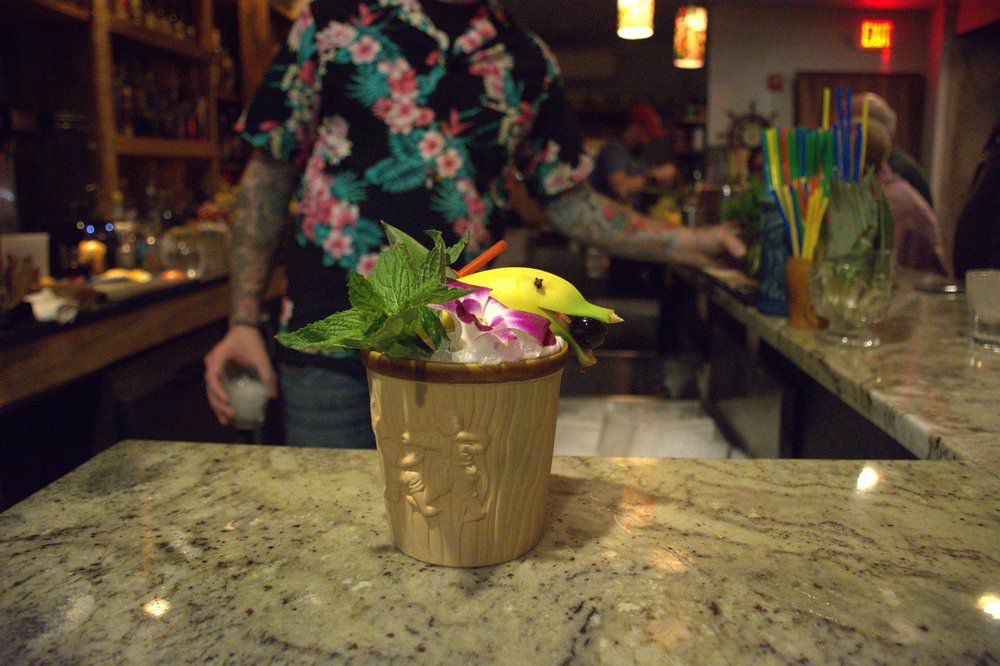 A tropical drink with a flower and banana garnish.