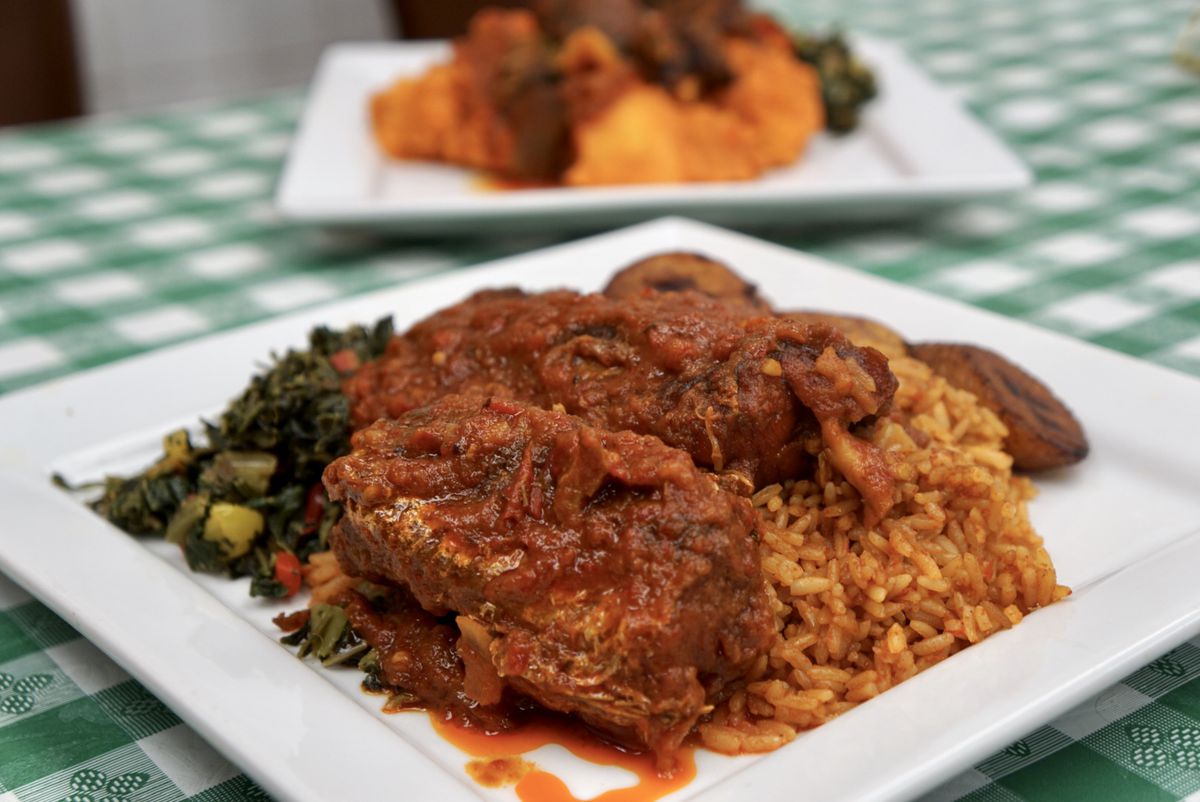 Rice, stewed meat, and cooked greens on a square white plate with green checker tablecloth.