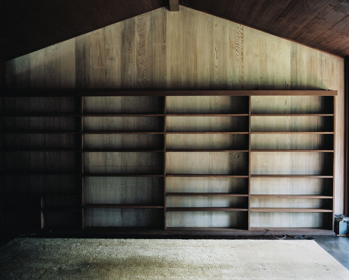 An interior wall of a home, an empty bookshelf. 