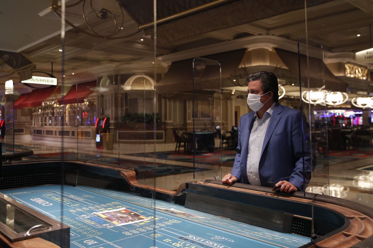 Bill Hornbuckle, acting CEO and president of MGM Resorts International, stands between acrylic barriers used as a coronavirus safety precaution at a craps table in the closed Bellagio Hotel and Casino.