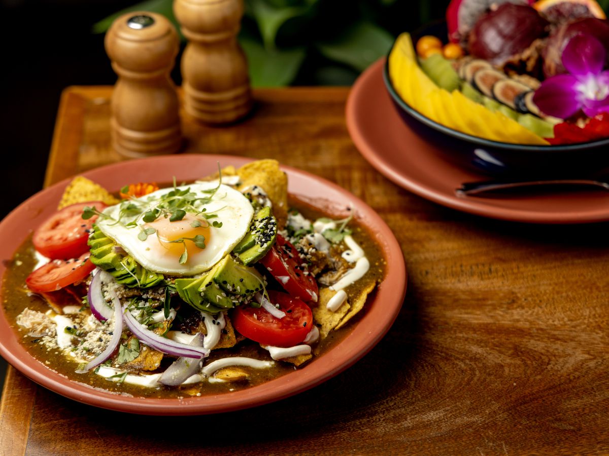 Ojo de Agua’s chilaquiles, topped with a fried egg, cilantro, onions, and verde salsa, with an acai bowl topped with fresh fruit on the side.