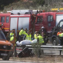 Undertaker workers carry the body of a person killed during a bus accident on the AP7 highway that links Spain with France along the Mediterranean coast near Freginals halfway between Valencia and Barcelona, Sunday, March 20, 2016. A bus carrying university students back from a fireworks festival crashed Sunday on a main highway in northeastern Spain, killing 14 passengers and injuring 30 others, a Catalonian official said. 