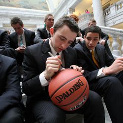 Nick Emery signs a basketball as he and his teammates from the Lone Peak High School basketball team, the top ranked high school team in the nation, visit the Capitol in Salt Lake City Friday, March 8, 2013.