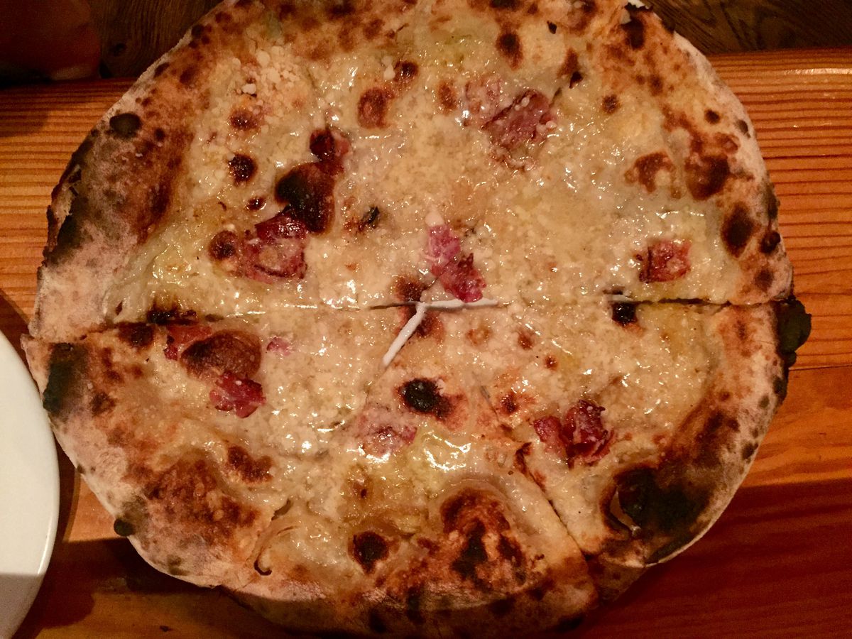 Neapolitan pizza with melted pork broth — akin to a soup dumpling — bacon, onion, and parmesan cheese from Razza